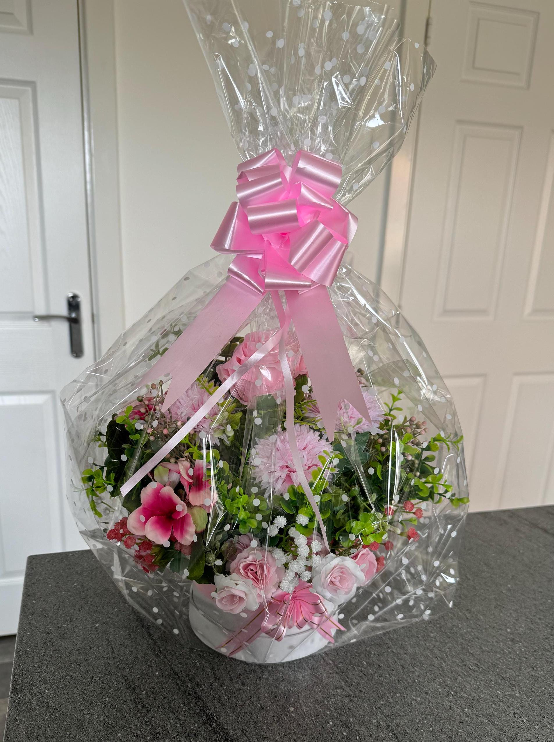 Small White hat box with pink artificial flowers and lots of greens.