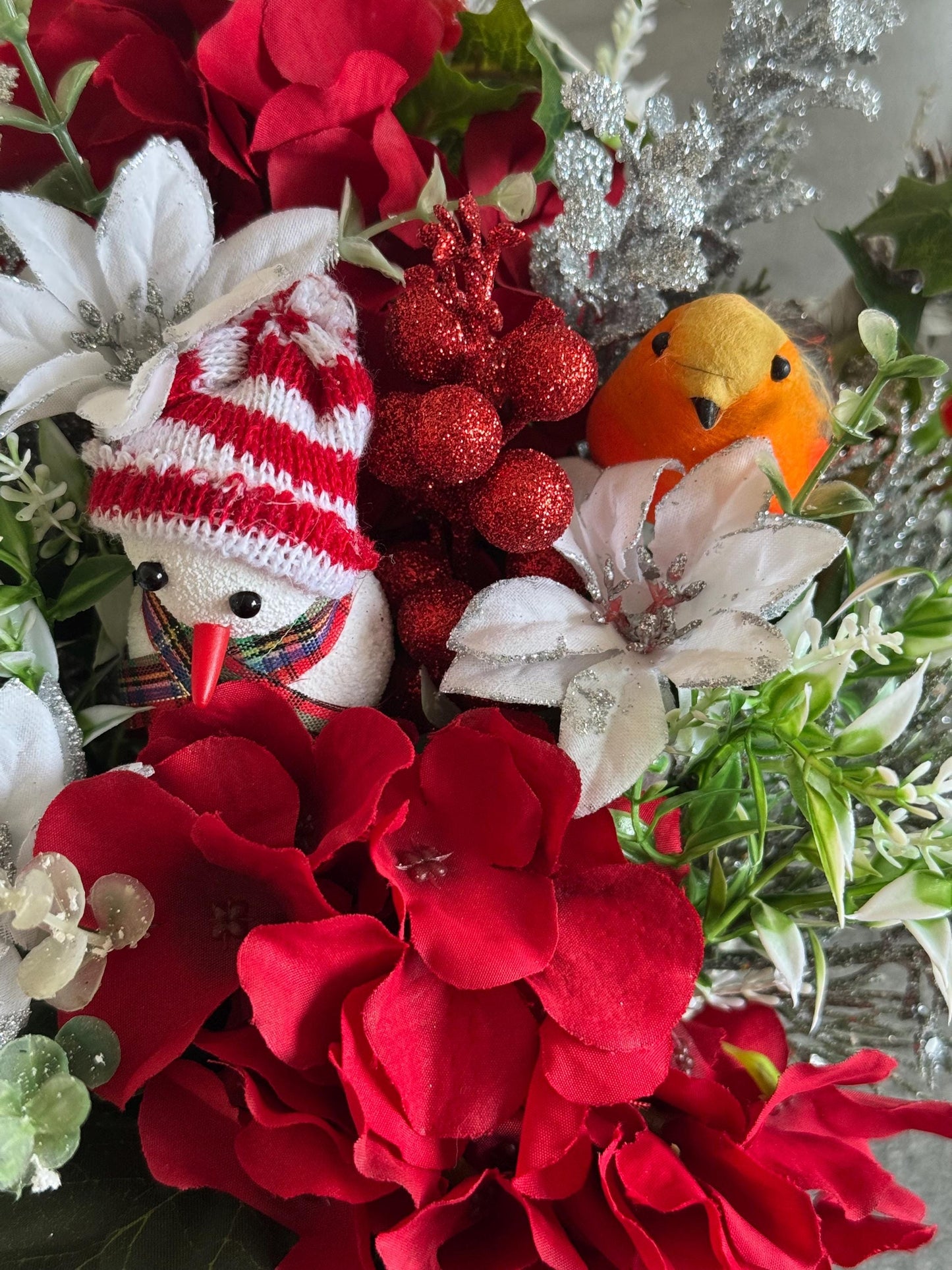 Small Christmas hat box filled with red artificial flowers and silver foliage. It comes with a snowman and a robin