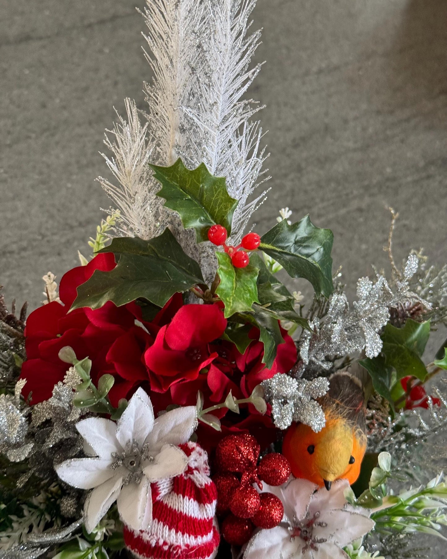 Small Christmas hat box filled with red artificial flowers and silver foliage. It comes with a snowman and a robin