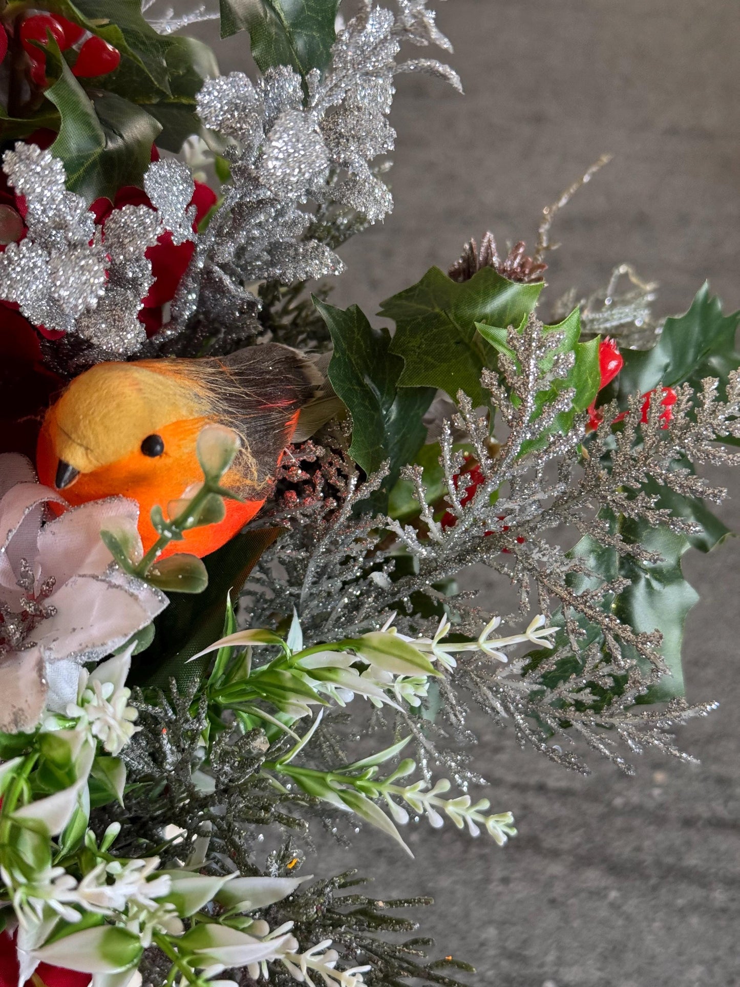 Small Christmas hat box filled with red artificial flowers and silver foliage. It comes with a snowman and a robin