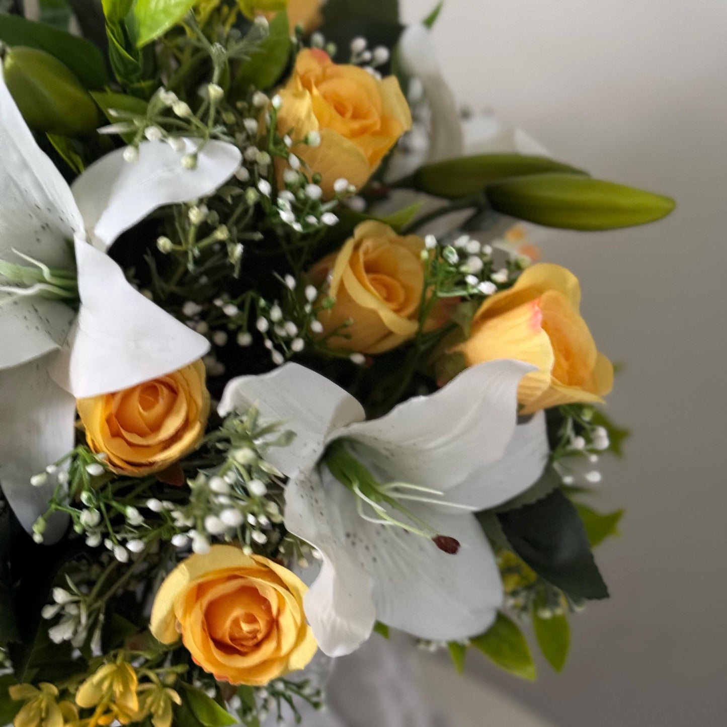 Artificial wedding bridal bouquet with white lilys, yellow rosebuds and foliage