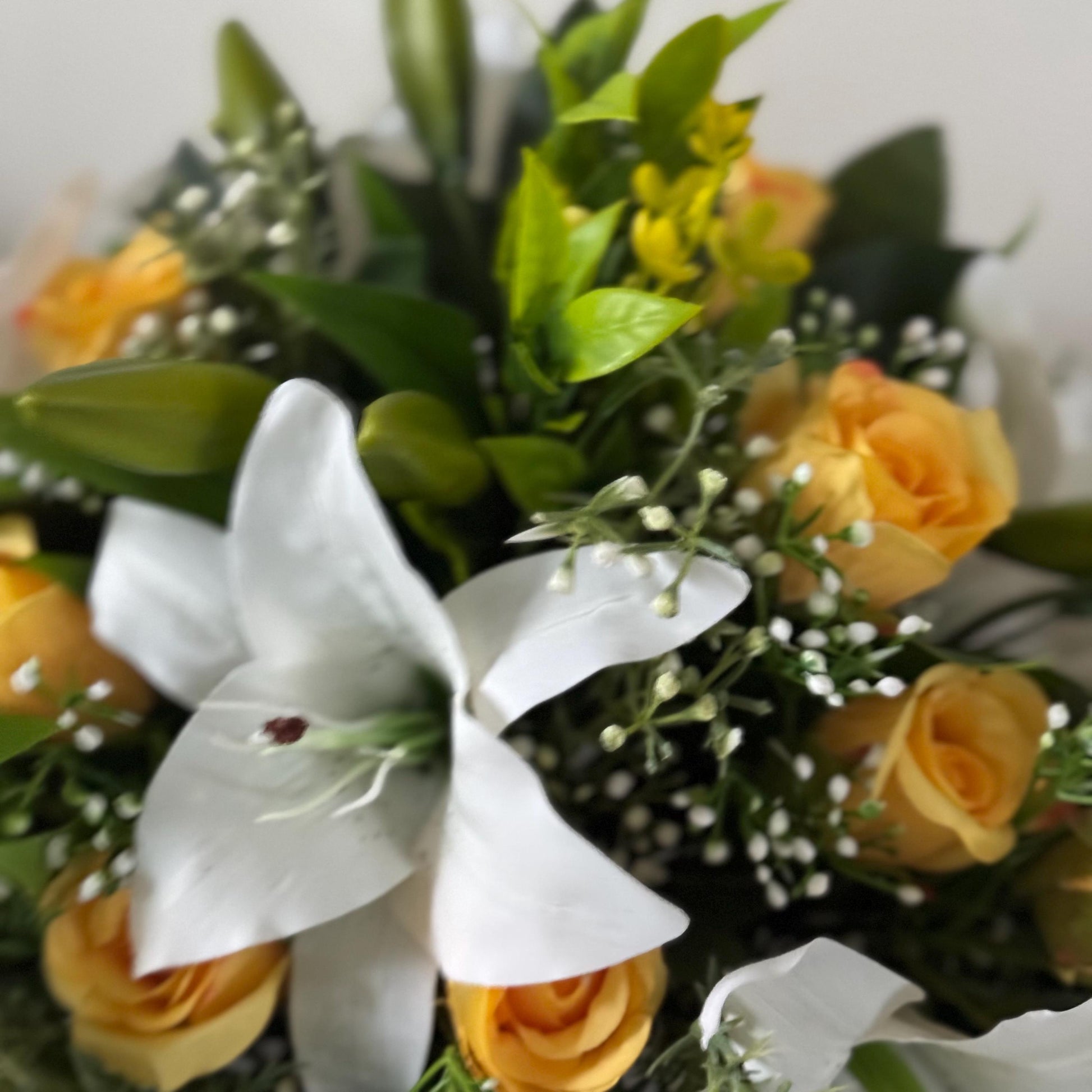 Artificial wedding bridal bouquet with white lilys, yellow rosebuds and foliage