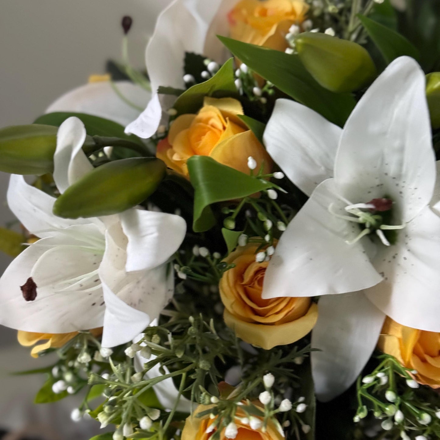 Artificial wedding bridal bouquet with white lilys, yellow rosebuds and foliage