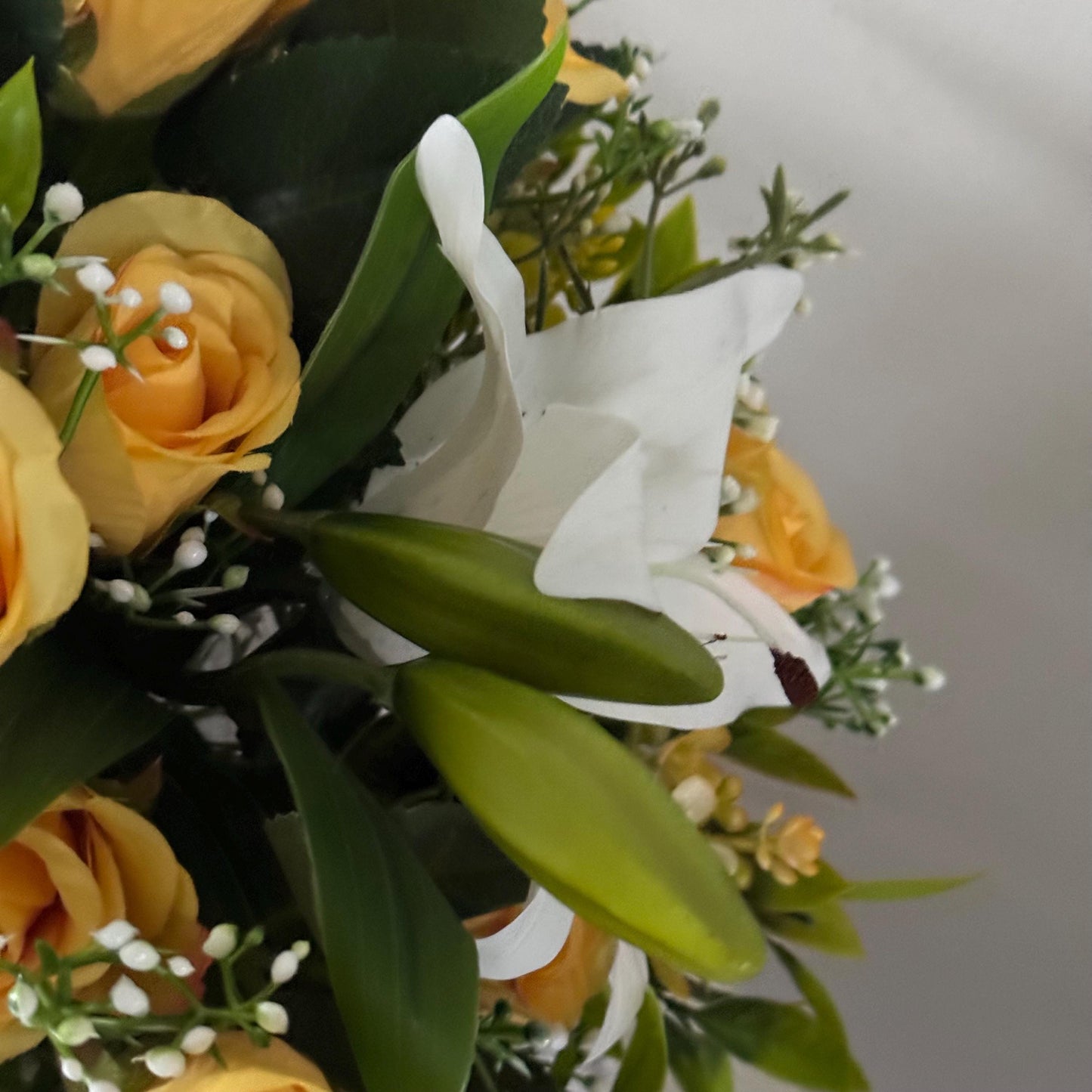 Artificial wedding bridal bouquet with white lilys, yellow rosebuds and foliage